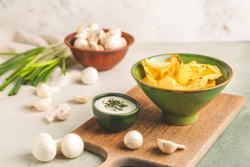 Tasty potato chips, mushrooms and sour-cream with herbs on table