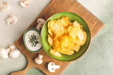 Tasty potato chips, mushrooms and sour-cream with herbs on table