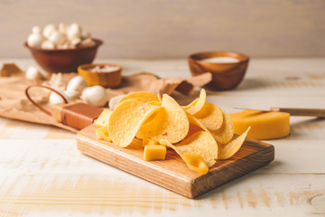 Tasty potato chips with cheese on table