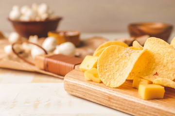 Tasty potato chips with cheese on table