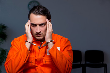Young convict man sitting in dark room
