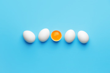 Broken egg among whole ones on color background. Concept of uniqueness