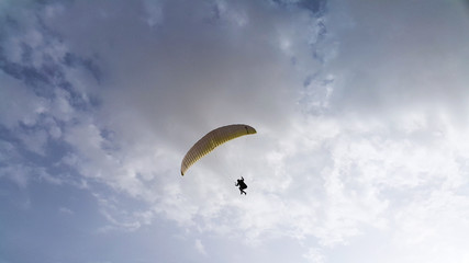 silhouette of man flying a paraglider in the blue sky - Paragliding is the recreational and competitive adventure sport of flying paragliders: lightweight, free-flying, foot-launched glider aircraft 