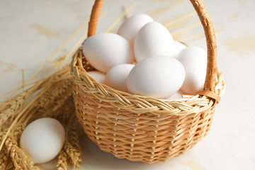 Basket with fresh raw eggs on table