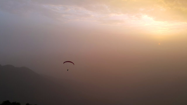 silhouette of man flying a paraglider in the blue sky - Paragliding is the recreational and competitive adventure sport of flying paragliders: lightweight, free-flying, foot-launched glider aircraft © Ayman