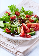 Healthy Salad with Cucumber, various Tomatoes and Olives on bright wooden Background. Healthy Snack Idea. 