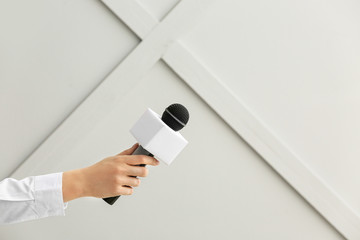 Journalist's hand with microphone on grey background