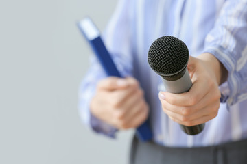 Journalist with microphone on grey background, closeup