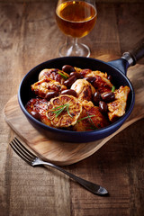 Grilled chicken pieces with kalamata olives and fresh rosemary. Rustic wooden background. 