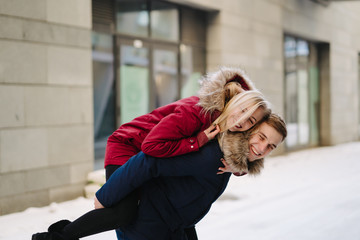 Young handsome guy giving girlfirend piggyback ride