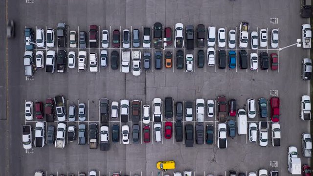 Aerial timelapse of cars driving in a busy parking lot viewed from top above