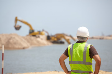 A site foreman supervising an excavator.