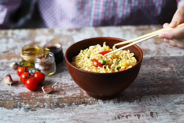 Selective focus. A man holds chopsticks with chinese noodles. Chinese noodle bowl with spices.
