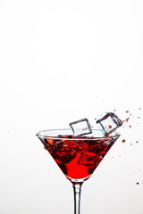 Closeup of Icecubes in Colorful Liquid. Falling to Goblet with Droplets. Against White Background.
