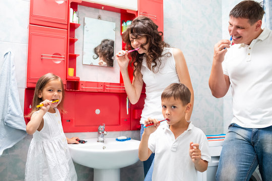 Family Concepts. Young VCaucasian Fa,ily with The Kids Having Fun in Bathroom While Brushing Teeth Together