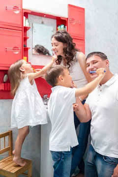 Family Concepts. Young VCaucasian Fa,ily with The Kids Having Fun in Bathroom While Brushing Teeth Together.