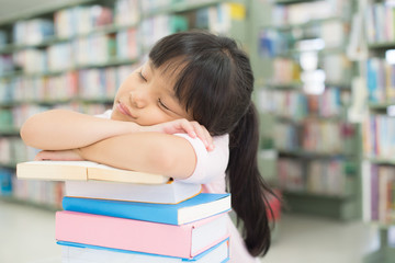 A girl reads a book until she sleeps in the library.