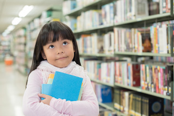 child girl holding a stack of books in the library