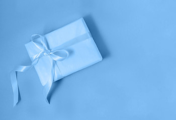 Gift box with a silk ribbon in trendy blue color. Flat lay style. Holiday gift concept. Color of the year 2020 concept. Copy space.