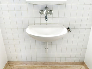 one white sink and faucet in public toilet