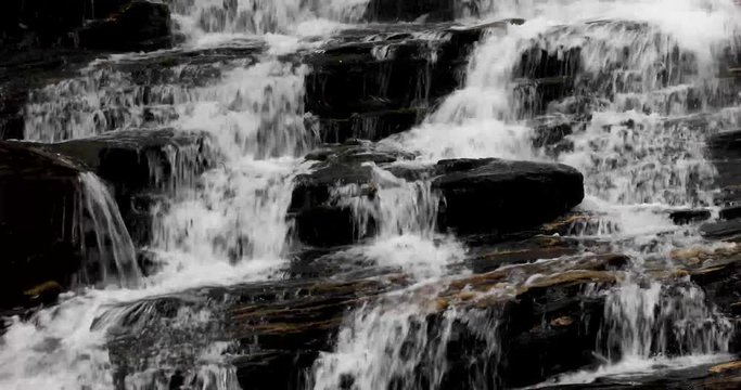 Water splashes and cascades down the rocks of a beautiful waterfall in this seamless video loop