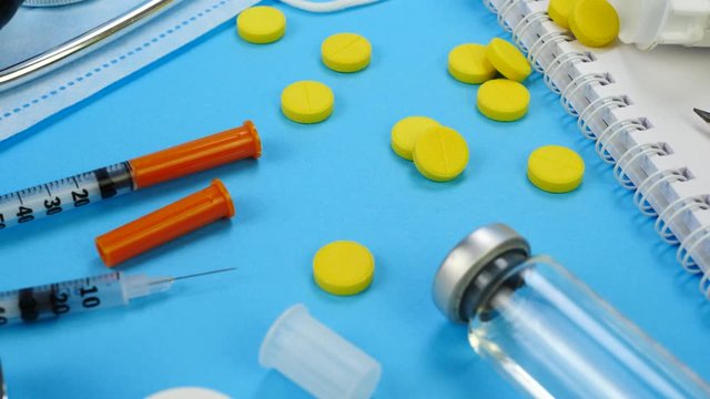Insulin syringe for insection, yellow tablets, stethoscope, vaccine, pencil paper notebook. Concept of health care, doctor, clinic or hospital. Medical Equipment on blue background