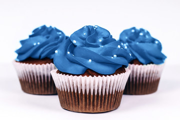 Three delicious cupcakes with icing in trendy blue color on isolated white background. Color of the year 2020 concept. Close-up.