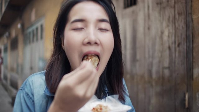 Beautiful Asian female tourists eating dumpling in old city of  Bangkok Thailand. Street food concept