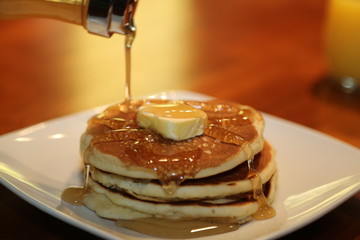 stack of pancakes with syrup and orange juice
