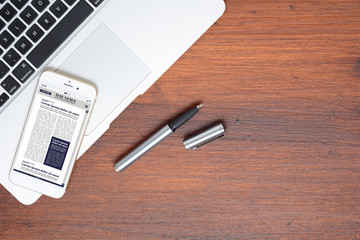 Office desk table and smartphone phone with Breaking News on screen