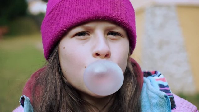 Beautiful teen girl with hat inflating bubble of chewing gum have fun bubble cheerful cute female fun caucasian gum glamour happy one portrait pretty teenager woman young slow motion