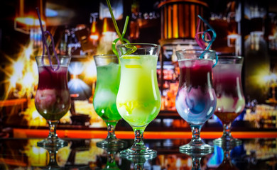 Cocktail glass splashing on dark toned smoky background or colorful cocktail in glass. Party club entertainment. Mixed light. Selective focus