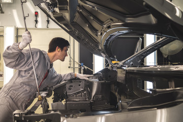 The employee of shop of painting of a body of the car checks quality. production line