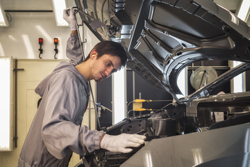 The employee of shop of painting of a body of the car checks quality. production line