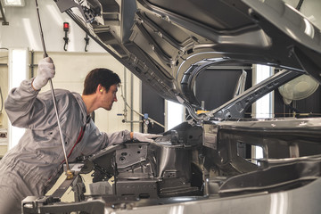The employee of shop of painting of a body of the car checks quality. production line