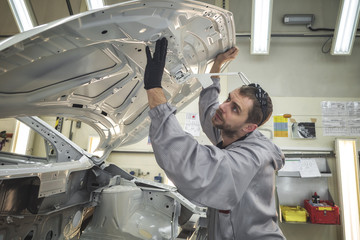 Obraz premium The employee of shop of painting of a body of the car checks quality. production line