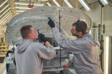 Employees of the shop painting the car body check the quality. production line