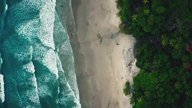 Beautiful 4K aerial drone seamless video loop / cinemagraph shot of a tropical Pacific paradise beach at the seaside in Costa Rica with endless moving waves.