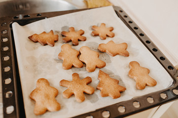 ready-made homemade hot cookies in the shape of a Christmas tree and a man on baking paper and a black baking tray