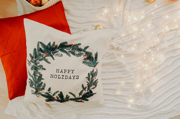 white bow with Christmas tree decor and happy holiday pisces on a white sofa with a blurred Christmas tree and bokeh lights on the background