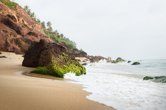 Couple walking at the cliff of Varkala along the coast with volcanic stones, India