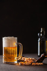 Glass of beer and pistachios on a plate on a dark background