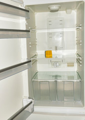 A piece of yellow old cheese lies on the empty shelves of the refrigerator. The concept of diet and hunger. Proper healthy eating..