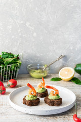 Canapes with avocado mousse and spicy shrimp on brown bread