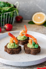 Canapes with avocado mousse and spicy shrimp on brown bread