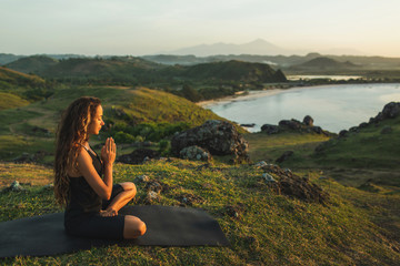 Woman doing yoga alone at sunrise with mountain and ocean view. Harmony with nature. Self-analysis and soul-searching - 308367667