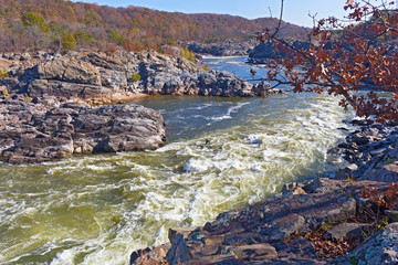 Full-flowing Potomac River after the rapids in Great Falls state park in Virginia, USA. Late autumn in the state park with trees at riverbanks.