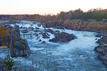 Potomac River waterfalls panorama at sunset in Great Falls state park in Virginia, USA. Great Falls state park in autumn with rocky riverbanks and deciduous forest.