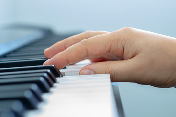 Fototapeta premium Male hand playing a keyboard piano during the day light