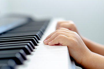 Fototapeta na wymiar Little kid toddler hand playing a keyboard piano during the day light